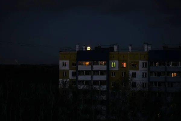 full moon  in the dark sky over the roofs of the night city