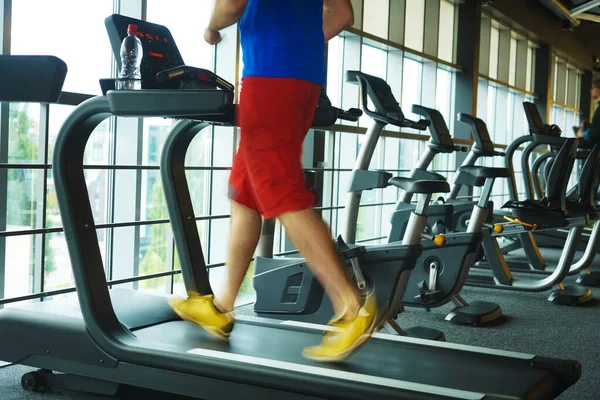 运动与减肥的主题 在体育馆里 穿着白色和黑色运动鞋的年轻强壮男子在模拟器上的脚部特写 — 图库照片
