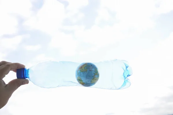 男性手拿着塑料瓶 蓝球在天空背景下 塑料构成的全球环境概念 — 图库照片