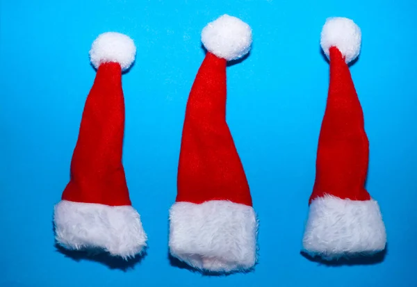 Tres Santa Claus Sombrero Rojo Aislado Sobre Fondo Papel Azul — Foto de Stock