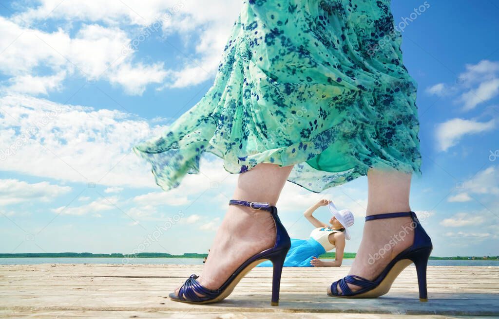 Beutiful young lady relax and enjoy summer at the seaside. other woman wearing high hills bliue shoes. beauty, fashion.