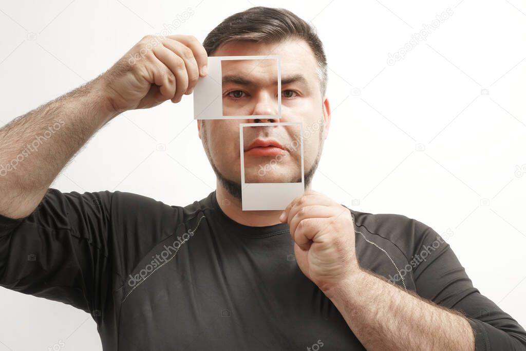 man wearing  black shirt and  holding  photos  in front of his face.  