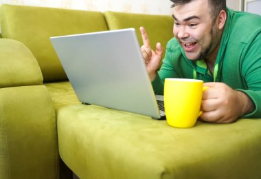 Serbest çalışan adam, dizüstü bilgisayarını kullanarak yalan söylemeyi ve kanepede dinlenmeyi başarıyor. Limon çayı ve dizüstü bilgisayarla çalıştıktan sonra, çalışan adam ev kavramında küçük işler yapıyor..