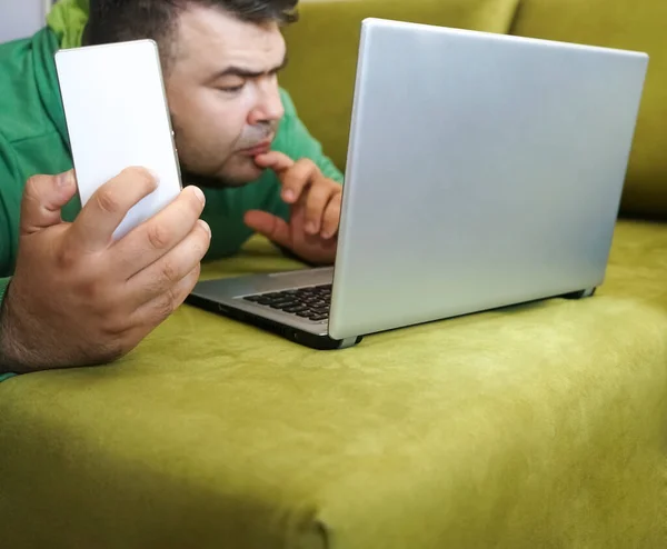Meşgul Adam Yeşil Koltukta Uzanıyor Cep Telefonu Dizüstü Bilgisayarla Çalışıyor — Stok fotoğraf