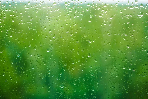 雨落在窗上 背景为绿树 玻璃上的雨滴 以绿光为背景 — 图库照片