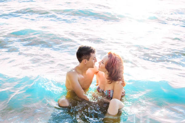 Sexy kiss in hot water. passionate couple in sitting in sunset sea shore or ocean. perfect sporty couple. man and woman outdoors. empty copy space for inscription. couple in love. summertime season