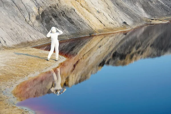 Astronaut woman wearing  helmet observing  planet Mars and  lake. female Astronaut on the Moon with reflection in water -  image for NASA.