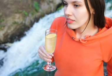 Genç kız nehirdeki bir bardaktan şarap ya da şampanya içer..