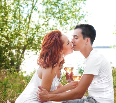 Aşk dolu bir çift nehir kıyısında gün batımında şarap ya da şampanya içiyor. Bir erkek arkadaş ve bir kız romantik bir randevuda, oturmuş bardaktan şampanya içiyorlar. Birbirine aşık çiftler. Erkek ve kadın öpüşüyor 