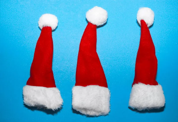 Tres Sombreros Rojos Santa Claus Aislados Sobre Fondo Papel Azul — Foto de Stock