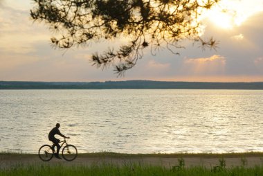 Akşamın renkli gündoğumu sırasında siluet bisiklet. Güzel güneş manzaralı siluet bisiklet arka plan kavramları, uygun motorcu duvar kağıdı, çevresel duygu