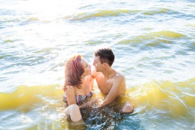 Sıcak suda seksi bir öpücük. Günbatımında deniz kıyısında ya da okyanusta oturan tutkulu bir çift. Mükemmel vücut ve sportif çift. Erkek ve kadın açık havada. Yazı için boş kopyalama alanı. Birbirine aşık çiftler. Yaz mevsimi