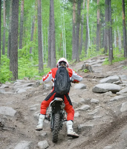 後ろの景色だ バイクでの極端なスポーツ エンデューロ自転車に乗って丘に乗ります 危険なスポーツや趣味 レーサー女性モチーフで赤と白の服 — ストック写真