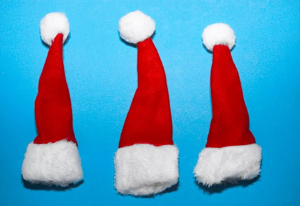 Tres Sombreros Rojos Santa Claus Aislados Sobre Fondo Papel Azul — Foto de Stock