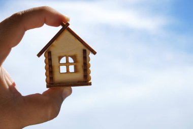 Erkek el ele tutuşması, mavi güneşli gökyüzünde tahta ev oyuncağı modeli. Yazı için boş kopyalama alanı 
