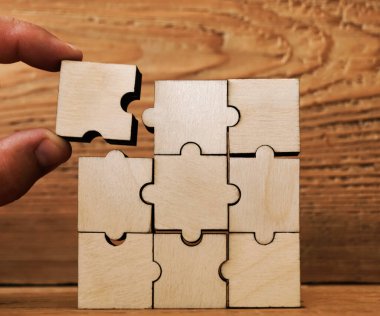 Adam eli, bitirme işi için tahta yapboz düzenleme işini halletti. Sorunu çözme ve başarı planı kavramı. İş başarısı konsepti. tüm kare