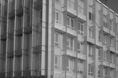 Modern mimarinin soyut bir parçası, camdan ve betondan yapılmış duvarlar. Mavi arka planda balkonu olan modern mavi ve yeşil bir bina.. 