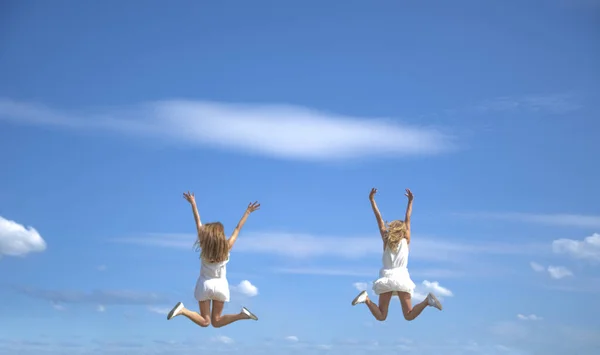 Traseira Visão Traseira Duas Meninas Adolescentes Pulando Contra Céu — Fotografia de Stock
