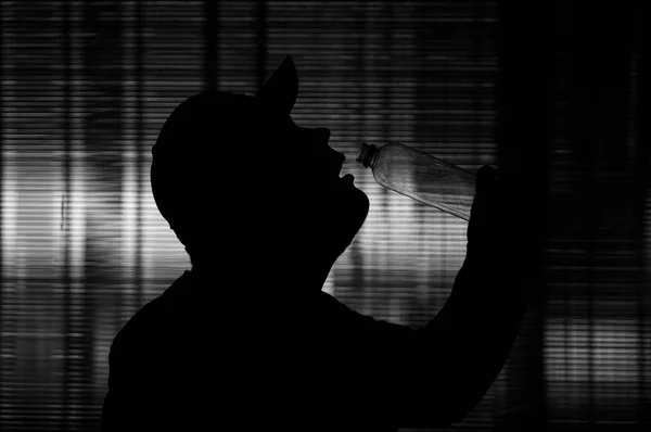 Sylwetka Młodego Człowieka Pijącego Wodę Plastikowa Butelka Scena Nocna — Zdjęcie stockowe