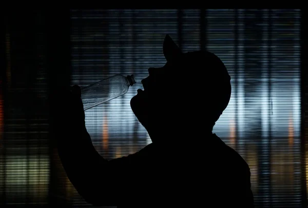 若い男のシルエット飲料水 ペットボトル 夜のシーン — ストック写真