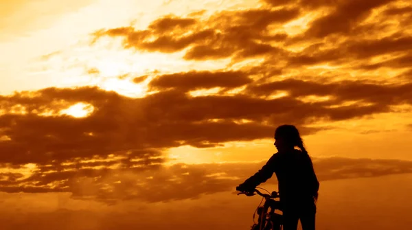 小女孩和自行车的轮廓 健康的生活方式 日落时骑婴儿车的人 女性望着日落的地平线 后视镜 — 图库照片