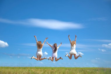 Üç gülümseyen kız sahada zıplıyor 