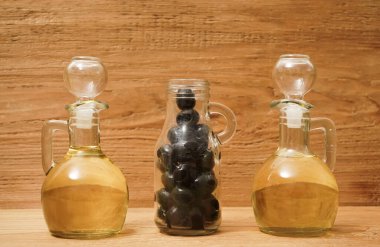 2 kavanoz zeytinyağı ve biraz da ahşap arka planda izole edilmiş siyah zeytin..                                                        