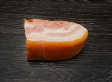 Domuz pastırmalı sığır eti ya da domuz eti. Sıcak tütsülenmiş et siyah tahta arka planda izole edilmiş.