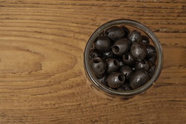Cam fiyonkta zeytin. Tahta arka planda izole edilmiş siyah zeytinler. boş kopyalama alanı.