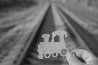 Demiryolu arka planında trenin ahşap figürü erkeklerin elinde. seyahat, lijistik ve çelme fikri.