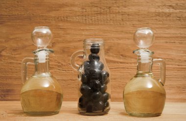 2 kavanoz zeytinyağı ve biraz da ahşap arka planda izole edilmiş siyah zeytin..                                                        