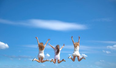 Üç gülümseyen kız sahada zıplıyor 