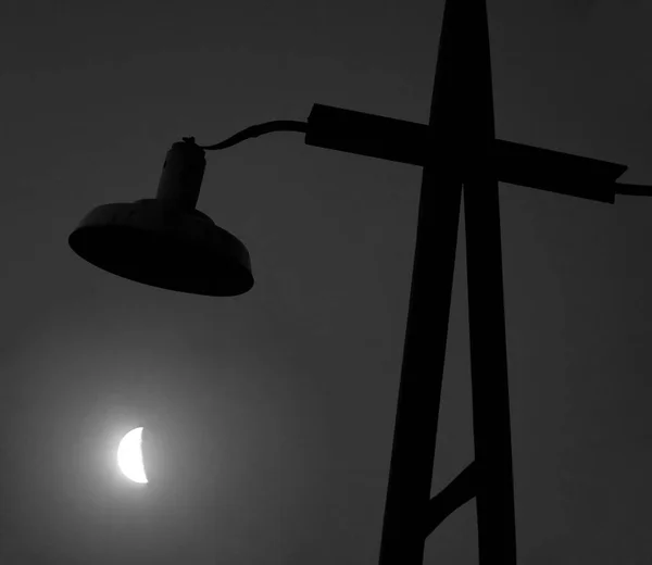 Lighted outdoor lamp against  moon  during sunset. Russia, Moscow region.