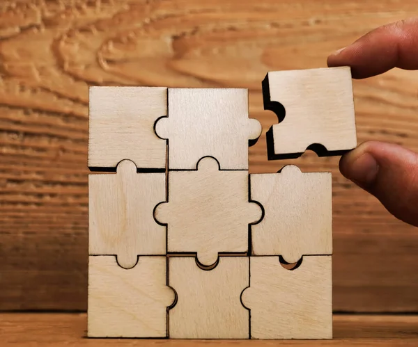 man hand putting wooden puzzle arranging stacking for finishing task. Concept of solve problem and success plan. business success concept. whole square