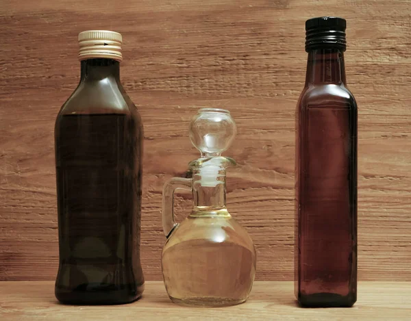 Achtergrond Van Drie Verschillende Glazen Olijfolieflessen Met Kurkstandaard Houten Plank — Stockfoto