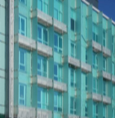 Modern mimarinin soyut bir parçası, camdan ve betondan yapılmış duvarlar. Modern mavi ve yeşil balkonlu bina