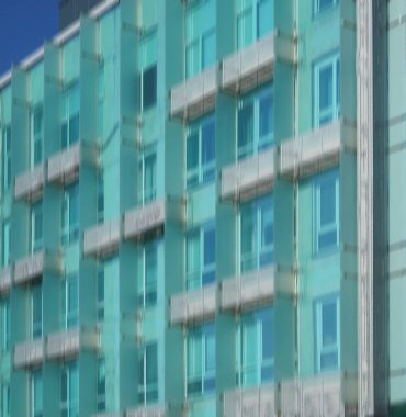 Modern mimarinin soyut bir parçası, camdan ve betondan yapılmış duvarlar. Modern mavi ve yeşil balkonlu bina