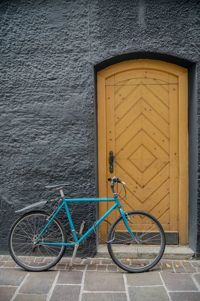 漂亮的现代风格的蓝色自行车靠近棕色或黄色的木门 灰色混凝土墙背景 Innsbruck Austria — 图库照片