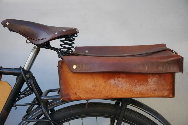 Photo old vintage bike, which stands near the gray  wall. Close up of an old, worn-out bicycle frame in which leather, vintage, new brown seat, glove compartment. Behind is the trunk.