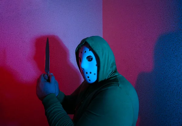 男人用刀攻击 手里拿着刀戴着黑色头巾的家伙冷兵器的威胁犯罪和抢劫的概念 背景上的霓虹灯 — 图库照片
