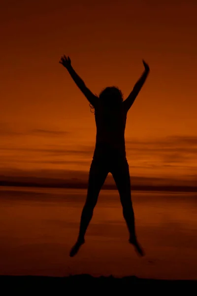 jumping and Dancing woman silhouette on the seaside during twilight. Silhouette of a girl jumping at sunset on the beach. summertime srason.