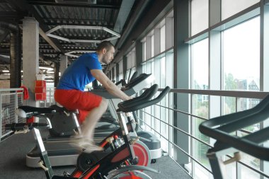 Spor salonunda bisiklet kullanan kaslı bir adam. Spor salonunda bisiklet kardiyo çalışması. yan görünüm.