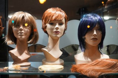 Rafta Peruklu Mannequin Heads 'in sırası. Gece sahnesi. Kuaförde zencefilli peruklu mankenler 