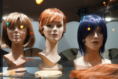 Rafta Peruklu Mannequin Heads 'in sırası. Gece sahnesi. Kuaförde zencefilli peruklu mankenler 