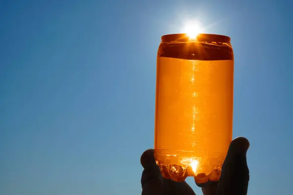 Человеческая Рука Держит Оранжевую Банку Против Солнца — стоковое фото