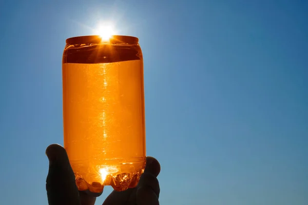 Menschliche Hand Hält Orangefarbene Dose Gegen Die Sonne — Stockfoto