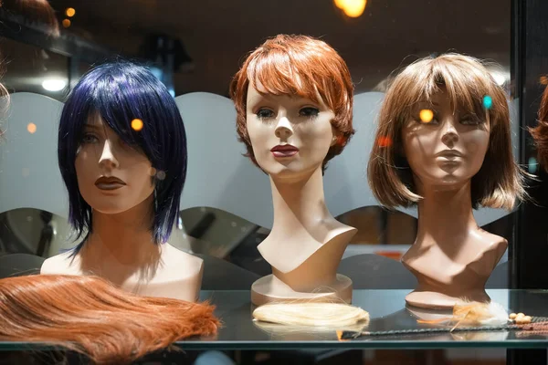 Row of Mannequin Heads with Wigs on the Shelf. night scene. Mannequins with ginger style wigs in  hair salon