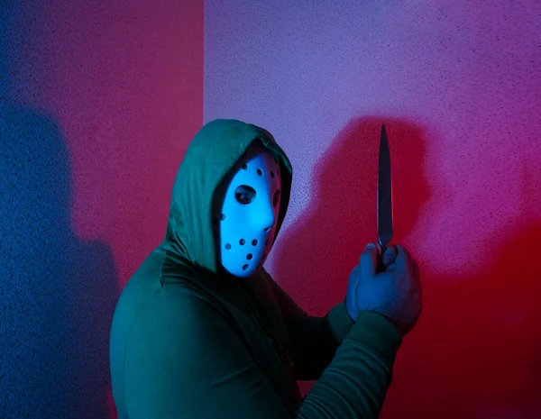 男人用刀攻击 手里拿着刀头戴黑色头巾的家伙冷兵器的威胁犯罪和抢劫的概念 背景上的霓虹灯 — 图库照片