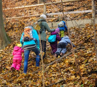 İki anne ve çocukları sonbahar parkında yürüyüş yapıyorlar. Arka plan