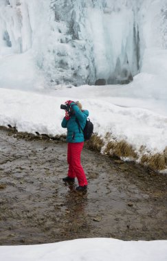 Profesyonel dijital kameralı kadın kış boyunca nehirde. Kadın fotoğrafçı kış vakti nehrin yanında. Buzlu dağ